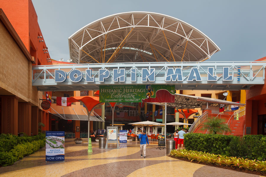 The grand entrance of Dolphin Mall greets visitors with its iconic blue signage, contemporary canopy, and vibrant colors—a visual reflection of Miami’s lively spirit. Under the bright, open architecture, guests arrive ready to explore this popular destination’s world of shopping, dining, and entertainment. The bustling courtyard hints at the excitement and welcoming atmosphere waiting inside, making Dolphin Mall a must-visit stop for travelers and locals alike.