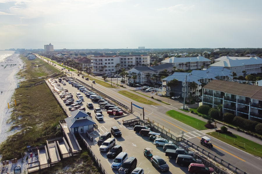 Aerial view of Scenic Gulf Drive in Miramar Beach, showing beach access areas, coastal traffic, and vacation properties lining the Emerald Coast.