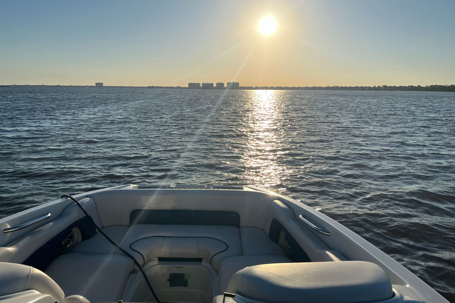 Sunset view from a boat on the Caloosahatchee River in Southwest Florida, with calm waters and distant shoreline reflecting the region’s coastal setting and boating lifestyle near Cape Coral and Fort Myers.
