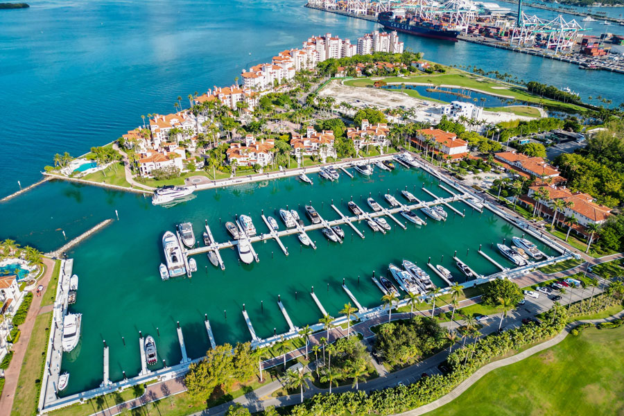 Aerial view of Fisher Island’s marina with docked yachts and waterfront residences, highlighting the island’s boat-access setting and its separation from the mainland despite its proximity to Miami.