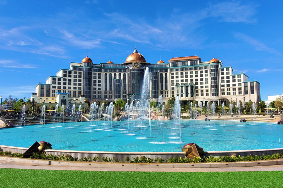 The fountain plaza in front of the Universal Helios Grand Hotel by Loews in Orlando, Florida, on a sunny day. Photo credit: Khairil Azhar Junos, licensed.