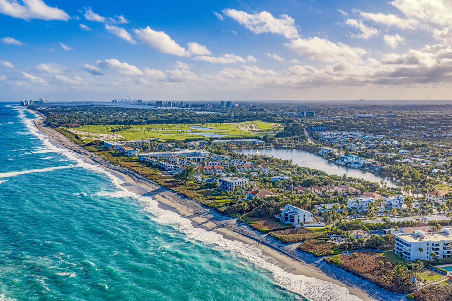 Aerial view of Juno Beach, Florida, showing the Atlantic coastline, beachfront homes, and inland waterways stretching toward neighboring communities in northern Palm Beach County.