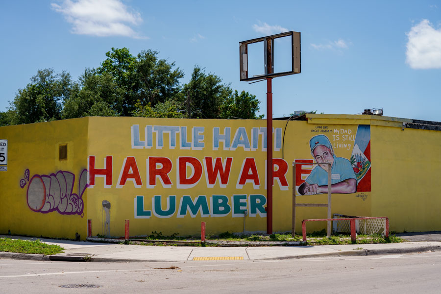 Street scene in Little Haiti, Miami, showing colorful mural-covered storefronts, neighborhood activity, and the area’s distinct local character. Photographed April 18, 2023.