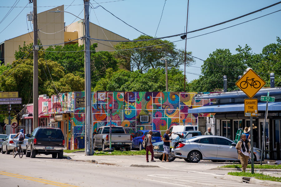 Street scene in Little Haiti, Miami, showing colorful mural-covered storefronts, neighborhood activity, and the area’s distinct local character. Photographed April 18, 2023.