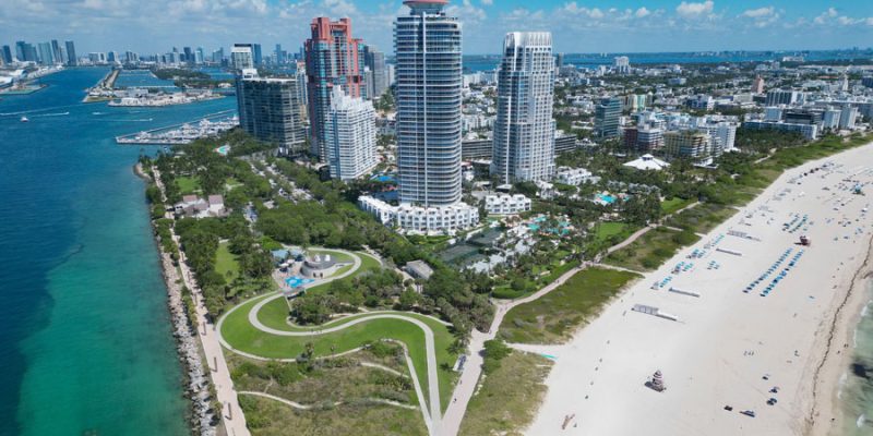 An aerial view of Miami Beach, Biscayne Bay, and the South Florida coastline shows the region’s mix of beaches, waterfront parks, marinas, high-rise hotels, and coastal neighborhoods. South Florida is defined by this blend of oceanfront scenery, urban skylines, tropical landscapes, and year-round outdoor travel.
