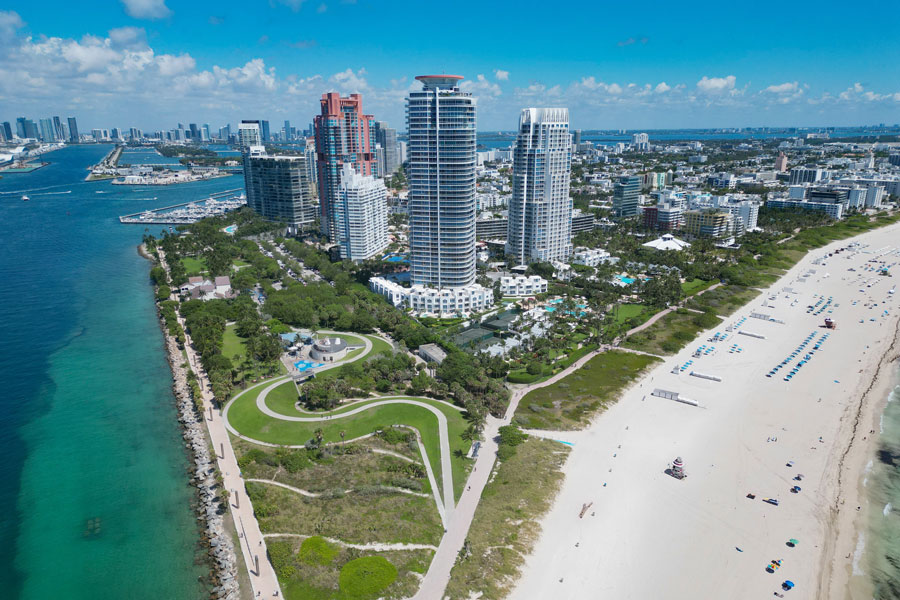 An aerial view of Miami Beach, Biscayne Bay, and the South Florida coastline shows the region’s mix of beaches, waterfront parks, marinas, high-rise hotels, and coastal neighborhoods. South Florida is defined by this blend of oceanfront scenery, urban skylines, tropical landscapes, and year-round outdoor travel.