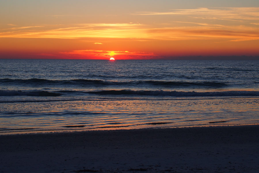 A colorful sunset settles over the Gulf Coast as the evening sky reflects across the water and shoreline. West-facing beaches are especially popular near sunset, when visitors gather along the coast to watch the sun disappear over the Gulf after a day of swimming, boating, fishing and exploring Florida’s coastal communities.