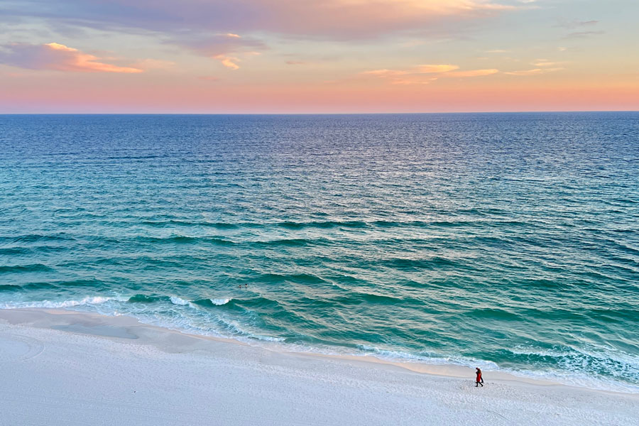 A quiet stretch of white-sand shoreline along Florida’s Emerald Coast meets clear turquoise Gulf waters beneath a soft evening sky. This part of Northwest Florida is known for its bright sand, vivid water, and long beach vistas that help define the Panhandle’s coastal landscape.