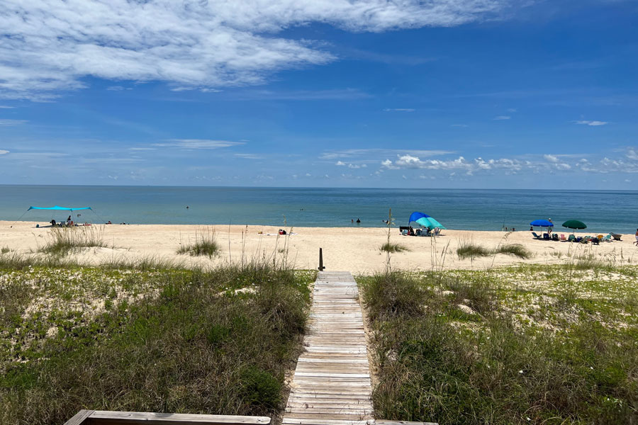 A wooden boardwalk crosses natural coastal dunes to the Gulf shoreline on St. George Island, where visitors enjoy swimming and relaxing along the broad sandy beach. The island’s combination of open shoreline, dune vegetation and relatively low-density development is characteristic of Florida’s Forgotten Coast. 