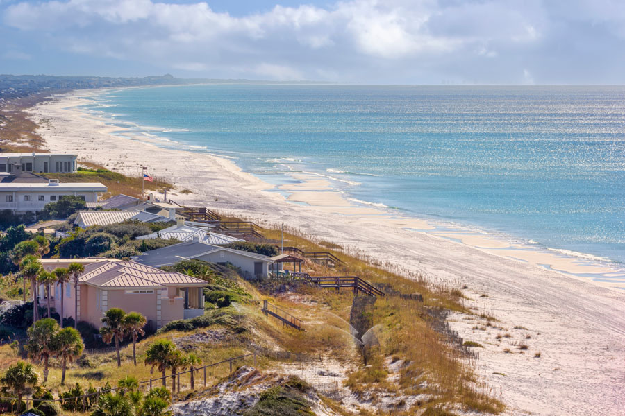 A sweeping view of the Florida Panhandle coastline near Panama City, where bright white sand stretches alongside the blue-green waters of the Gulf. The region’s long beaches, coastal dunes and clear Gulf waters are among the defining landscapes of Northwest Florida.