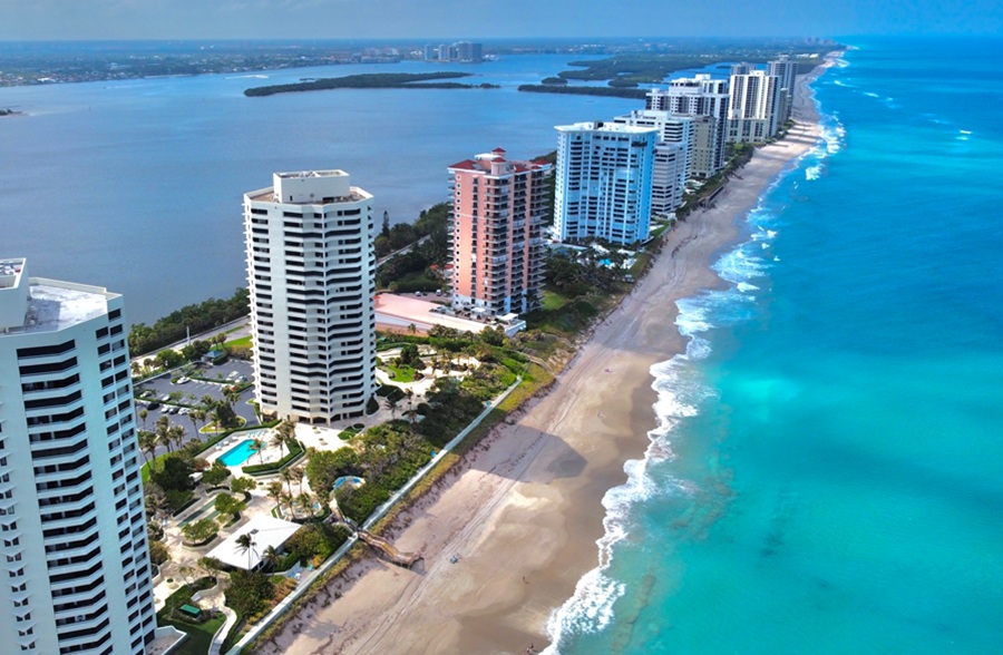 An aerial view of Singer Island shows its narrow barrier-island setting between the turquoise waters of the Atlantic Ocean and Lake Worth Lagoon. Oceanfront condominiums and resorts line the shoreline, while the lagoon and its mangrove islands stretch along the western side of the island in Palm Beach County.