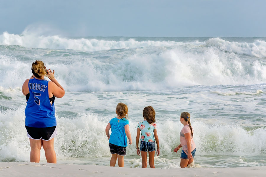 A family watches powerful surf roll ashore at Pensacola Beach as Hurricane Michael churned the Gulf of Mexico in October 2018. The scene illustrates the dramatic coastal conditions that tropical systems can produce along Florida’s Panhandle, even at locations outside a storm’s direct path.