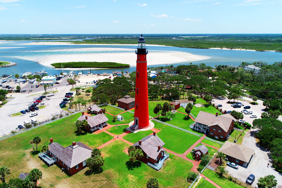 The Ponce de Leon Inlet Lighthouse rises 175 feet above the historic light station at Ponce Inlet, overlooking the meeting of the Atlantic Ocean and the inland waterways of Florida’s east coast. Completed in 1887, the distinctive red-brick tower is the tallest lighthouse in Florida and remains one of Volusia County’s most recognizable landmarks. The surrounding museum complex preserves historic keeper dwellings and other buildings associated with more than a century of maritime navigation along this stretch of coastline. Photo credit: Dennis MacDonald; licensed.